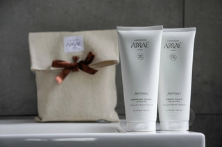 Crème et Gommage pour le corps avec une pochette en lin en arrière plan et dans un décor de salle de bain. 
Produits naturels et Made in France