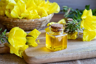 Petit flacon contenant de l'huile d'onagre avec des fleurs d'onagre posées autour sur une table