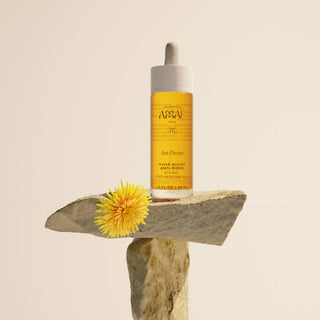 Huile Divine Anti-Rides Amaé photographiée seule en équilibre sur une pierre, flacon pipette, illustrant un soin visage naturel et anti-âge de qualité.